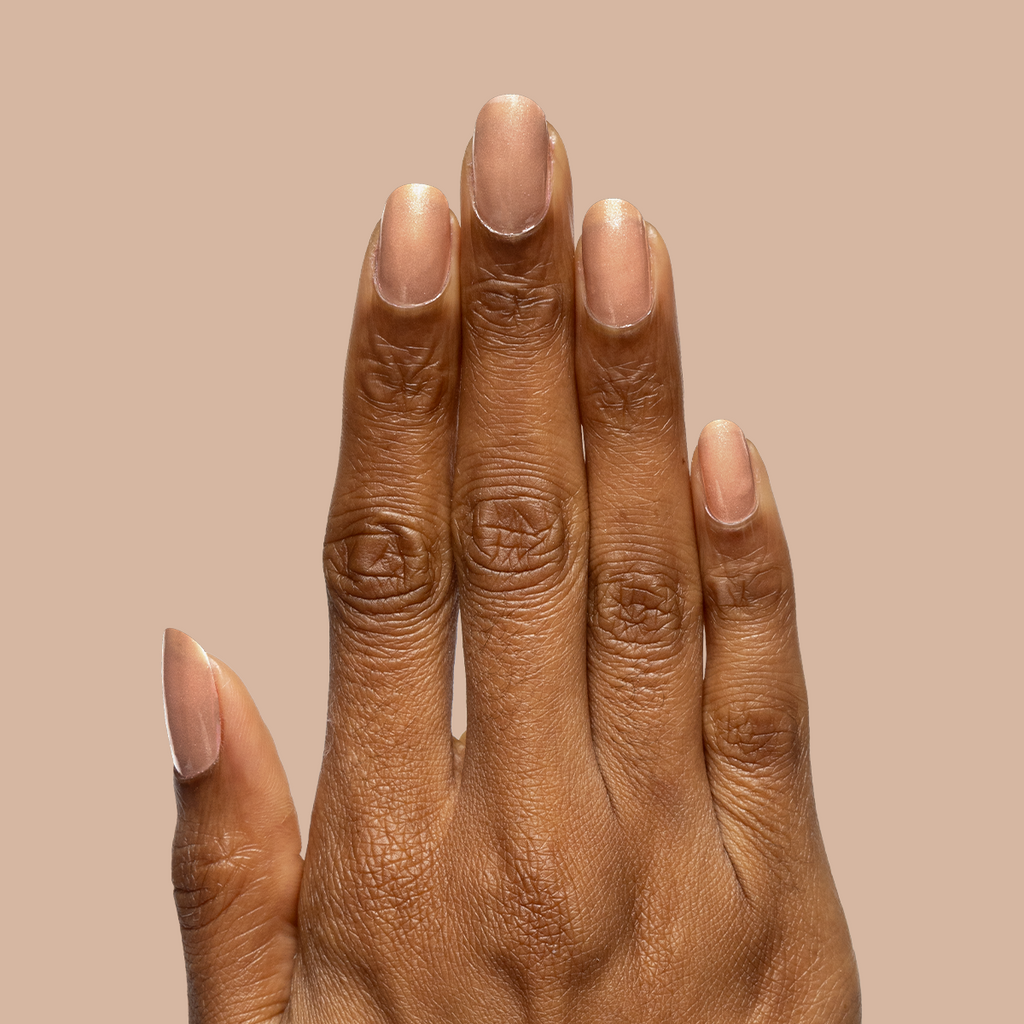 Hand with nails coated in sheer warm chestnut Coconut Shimmer Gloss gel polish on neutral beige background