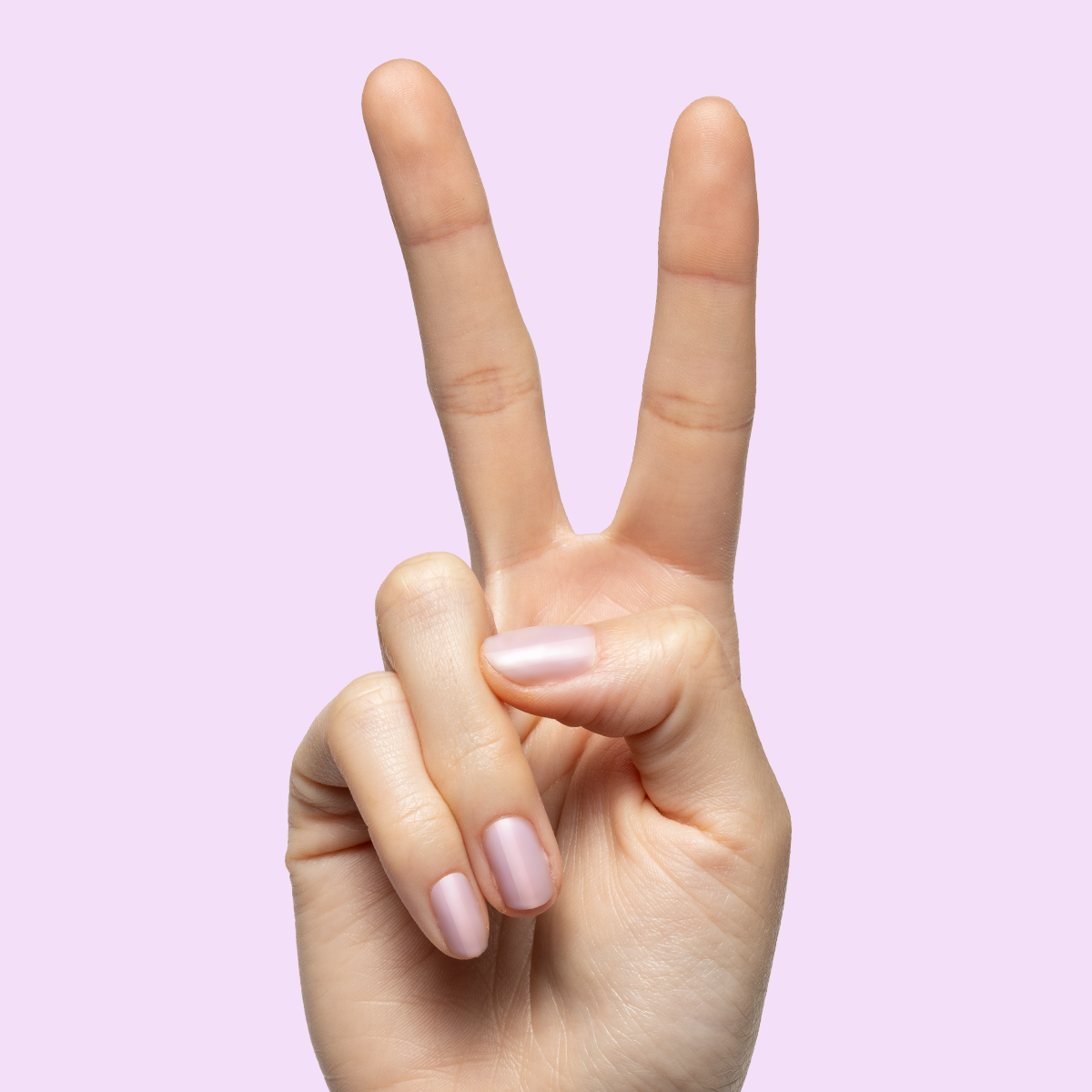 Hand showing peace sign with medium nails painted in cool milky lavender using Passionfruit Gloss polish on light purple background