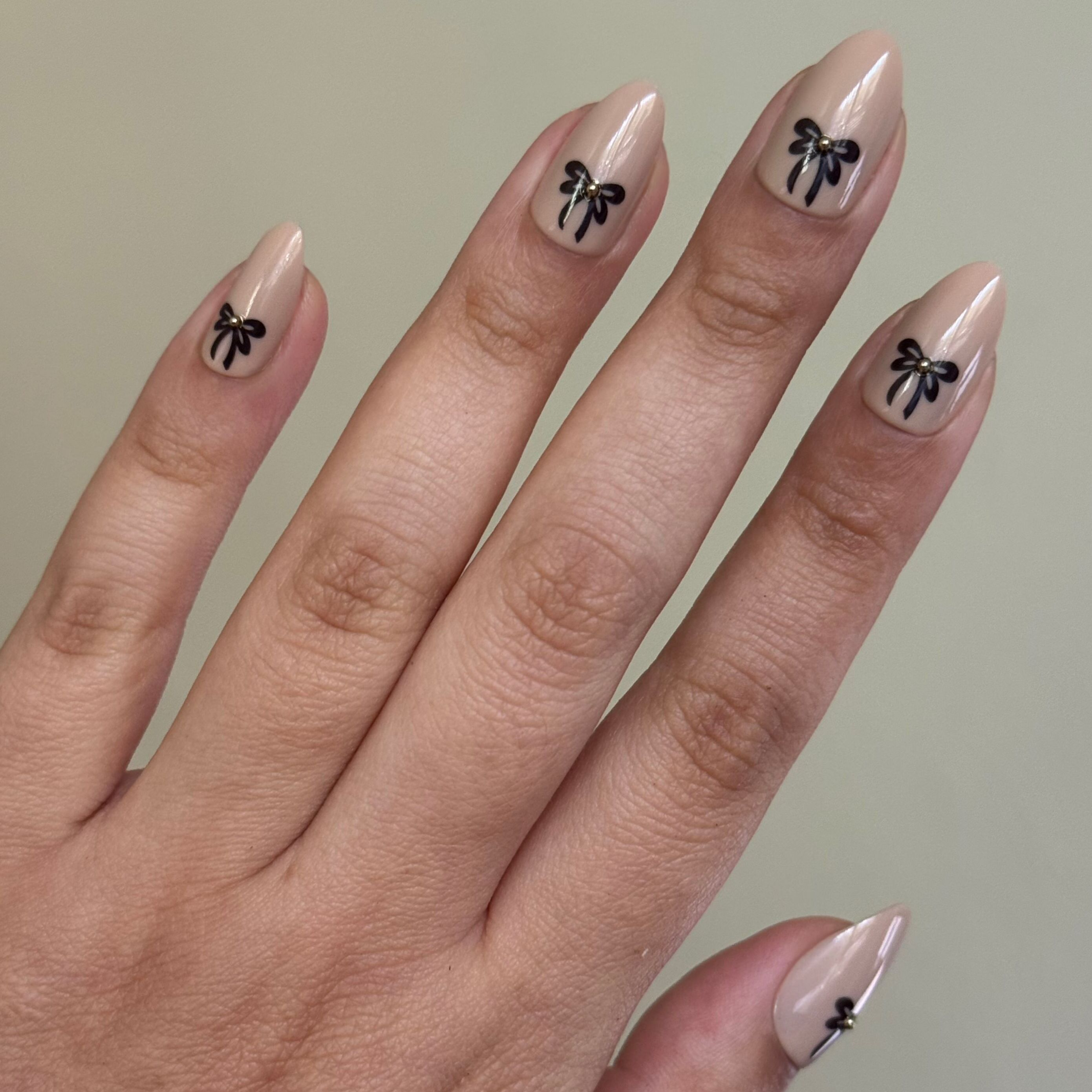 Little Gem Bows - Press On | Medium | Almond creamy beige nails with black bows and 3D gems for a stylish at-home manicure