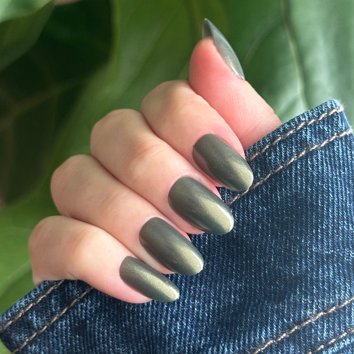 Hand with medium oval nails in Martini Chrome - Press-On showing deep olive green with golden shimmer manicure