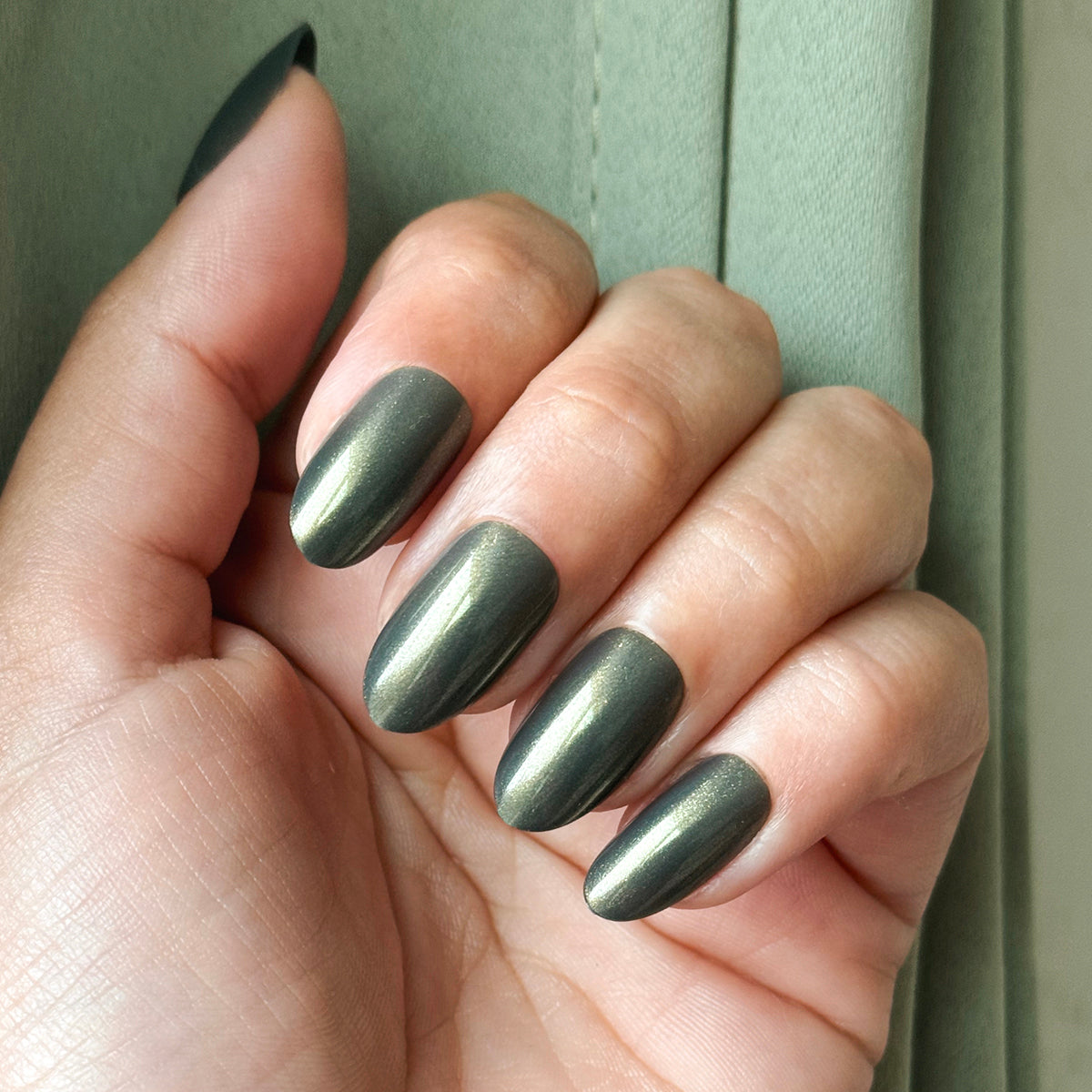 Martini Chrome - Press-On | Medium | Oval nails in deep olive green with golden shimmer press-on mani on hand against green background