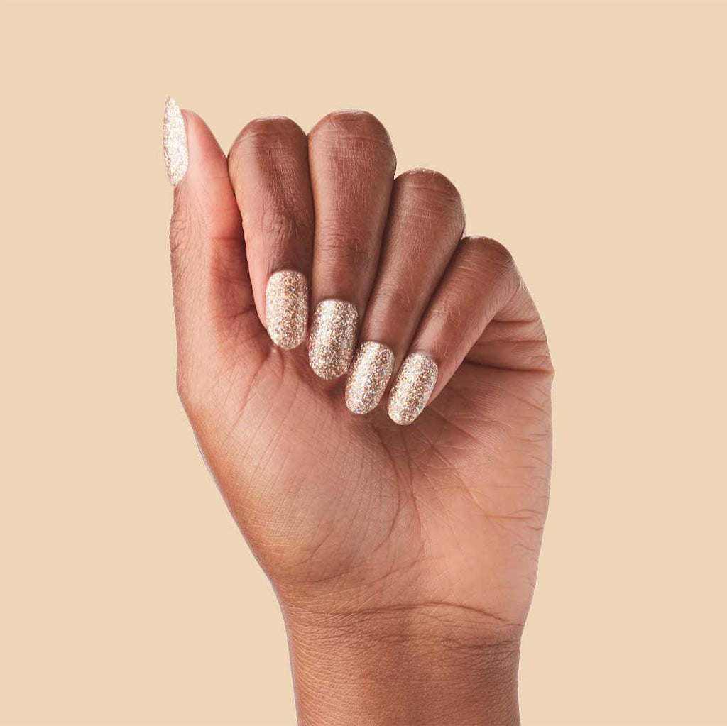 OBVI - Press-On | Medium | Oval hand showing medium oval false nails in shimmering gold glitter polish manicure