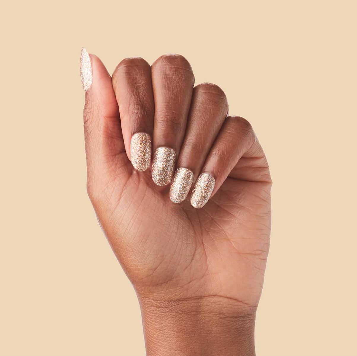 OBVI - Press-On | Medium | Oval hand showing medium oval false nails in shimmering gold glitter polish manicure