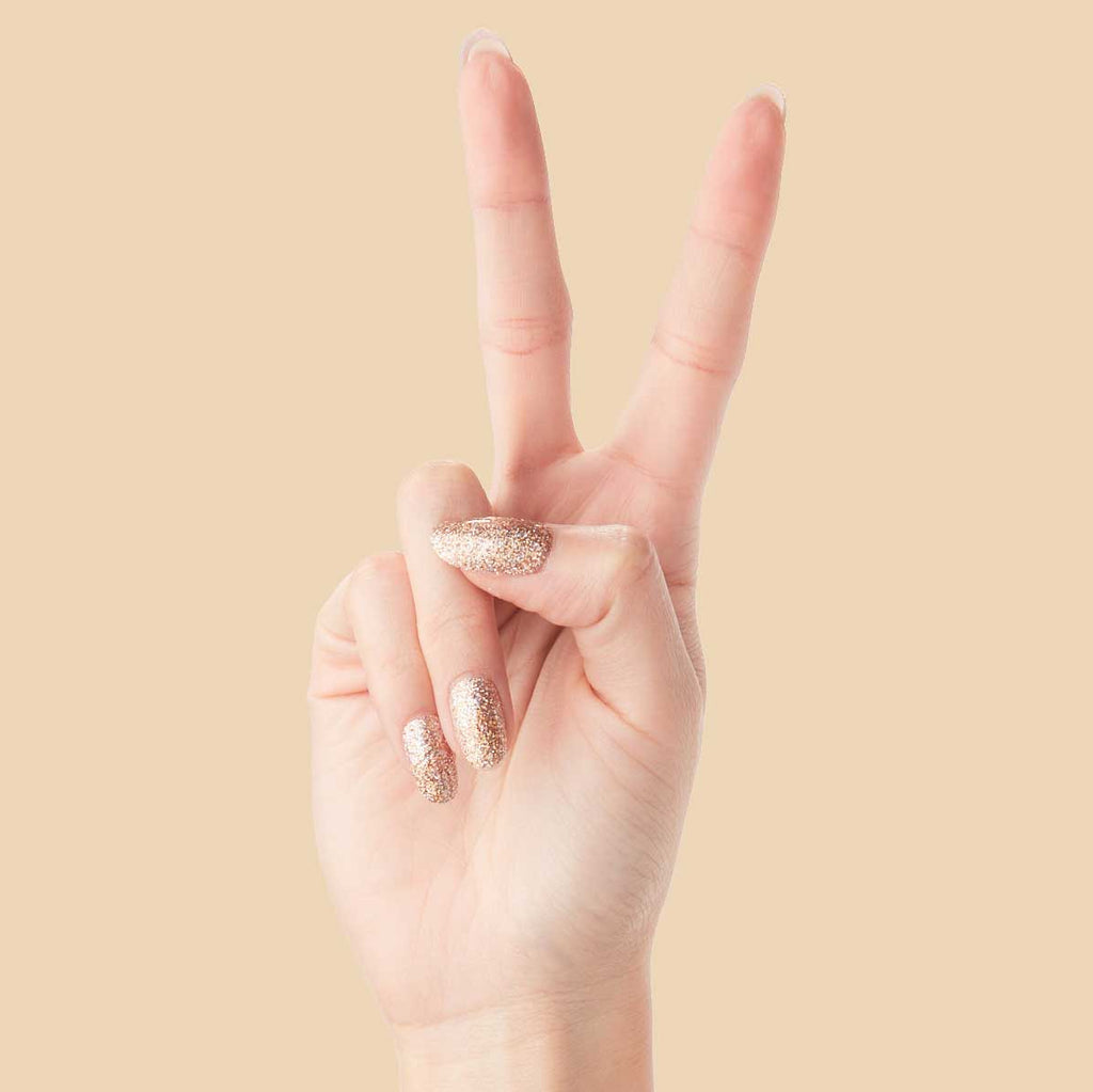 OBVI - Press-On | Medium | Oval hand showing medium oval false nails in sparkling gold glitter for a festive mani
