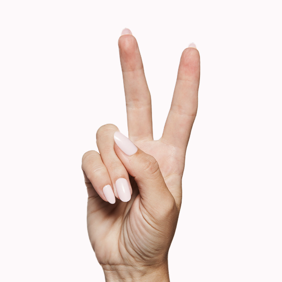 Pink Sands - Press-On | Medium | Oval hand showing medium oval false nails in soft sun-bleached pink polish shade