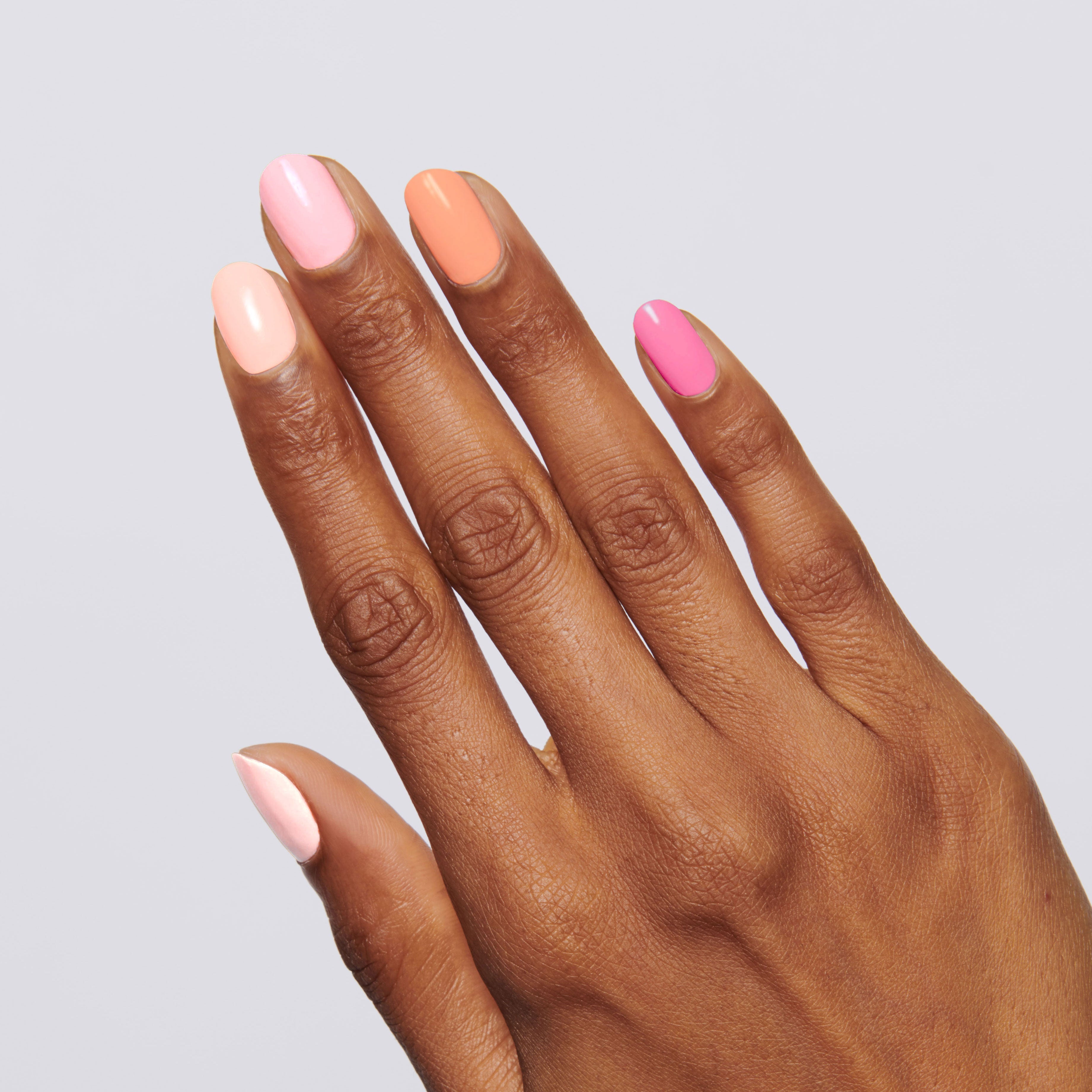 Hand with nails painted in pink and peach shades from the Summer Sorbet Set showing a fresh manicure