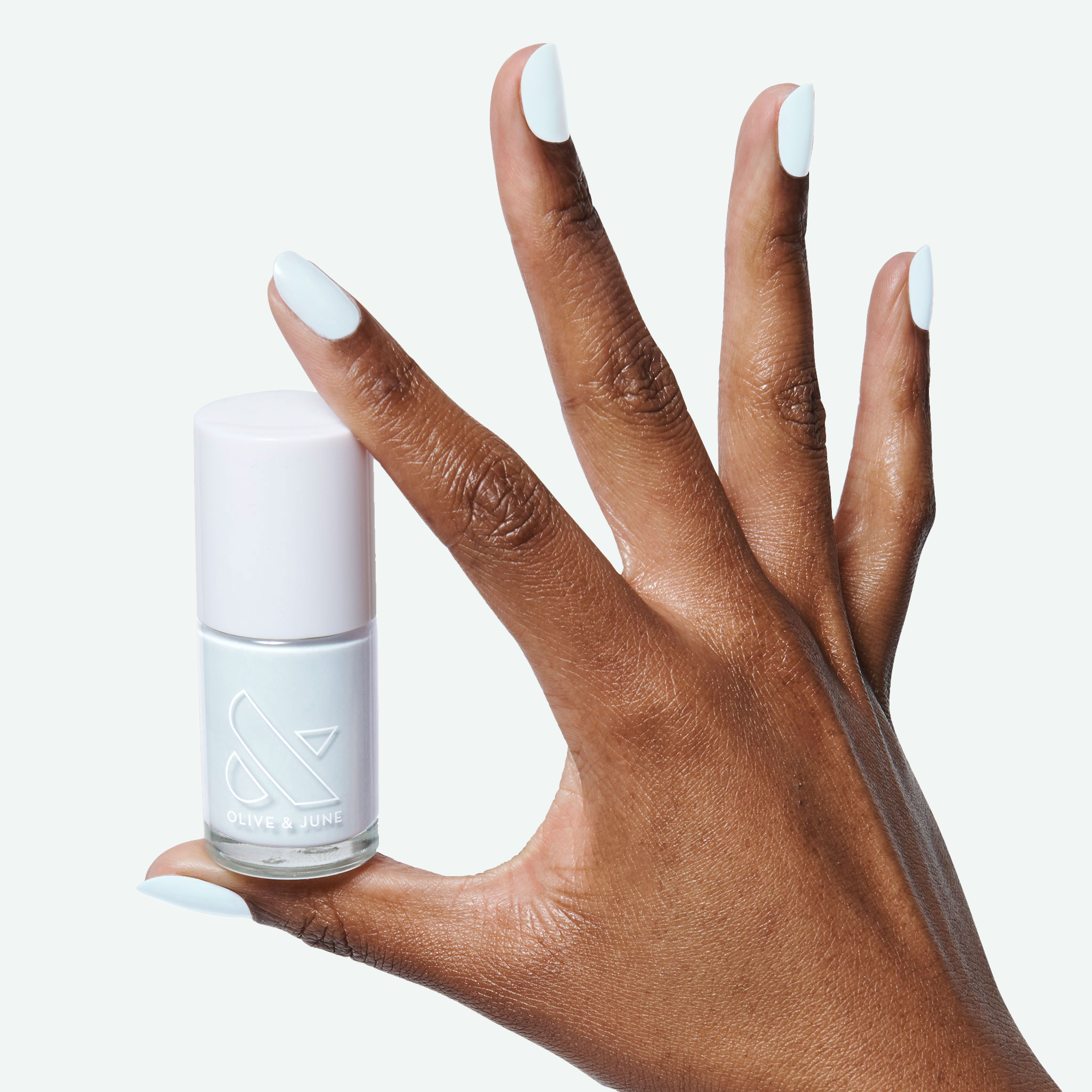 Hand with smooth pale blue nails holding a bottle of Angelfish long-lasting polish by Olive and June