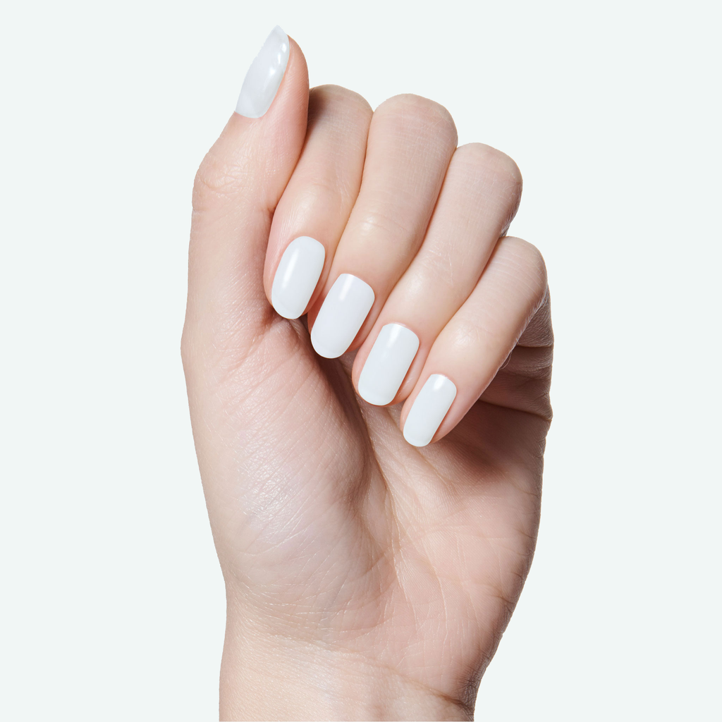 Hand with smooth glossy white nails showing an at-home manicure using Angelfish long-lasting polish by Olive and June