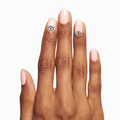 Hand with nude manicure featuring EYE LOVE YOUR MANI nail art stickers of eyes and lashes on medium skin tone