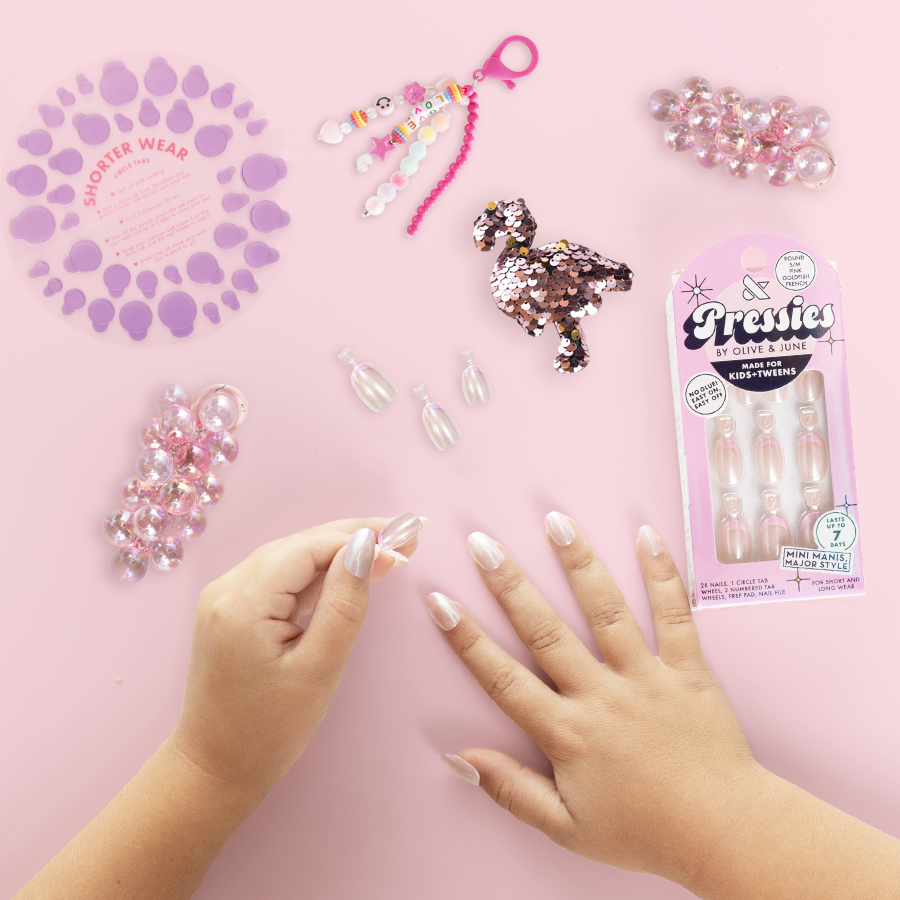 Pink Goldfish French - Pressies | Short Medium | Round showing hands applying iridescent pink tip press on nails on pink background