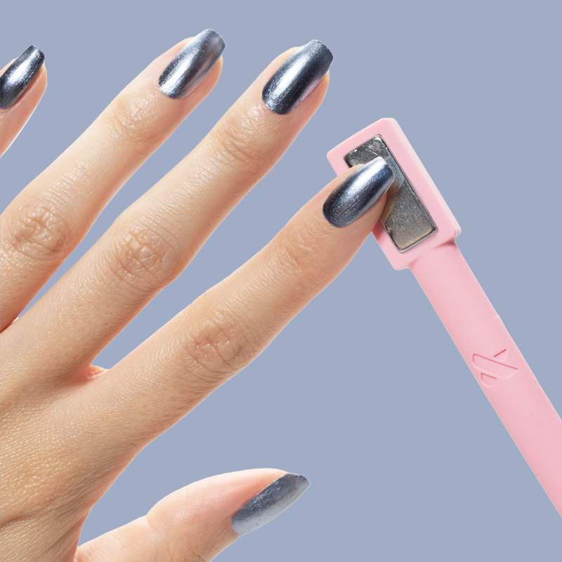 Hand with nails painted in Sapphire Velvet icy blue magnetic polish using pink rectangular magnet tool for mani effects