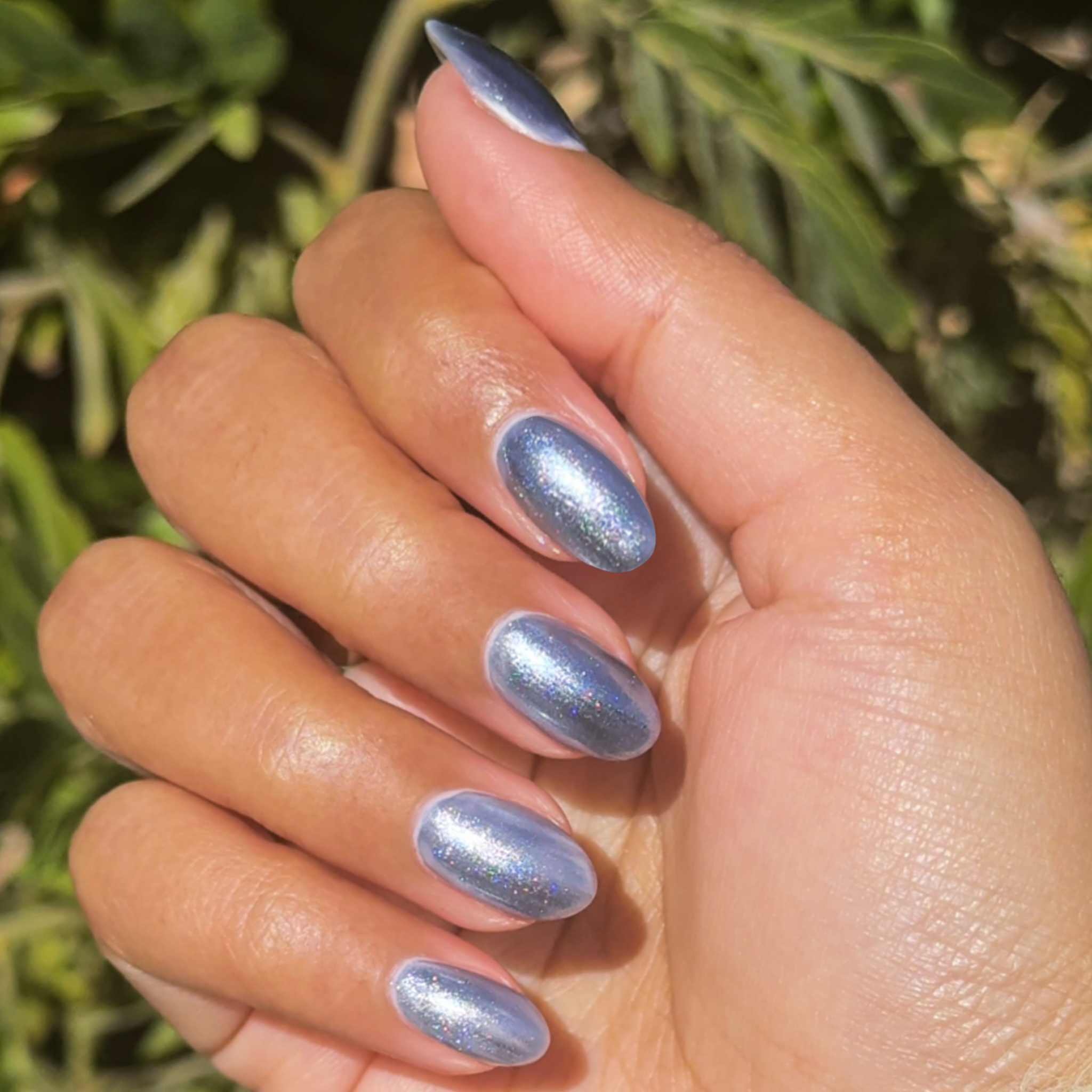 Hand with nails polished in Sapphire Velvet showing glossy icy blue shimmer for an at-home manicure look