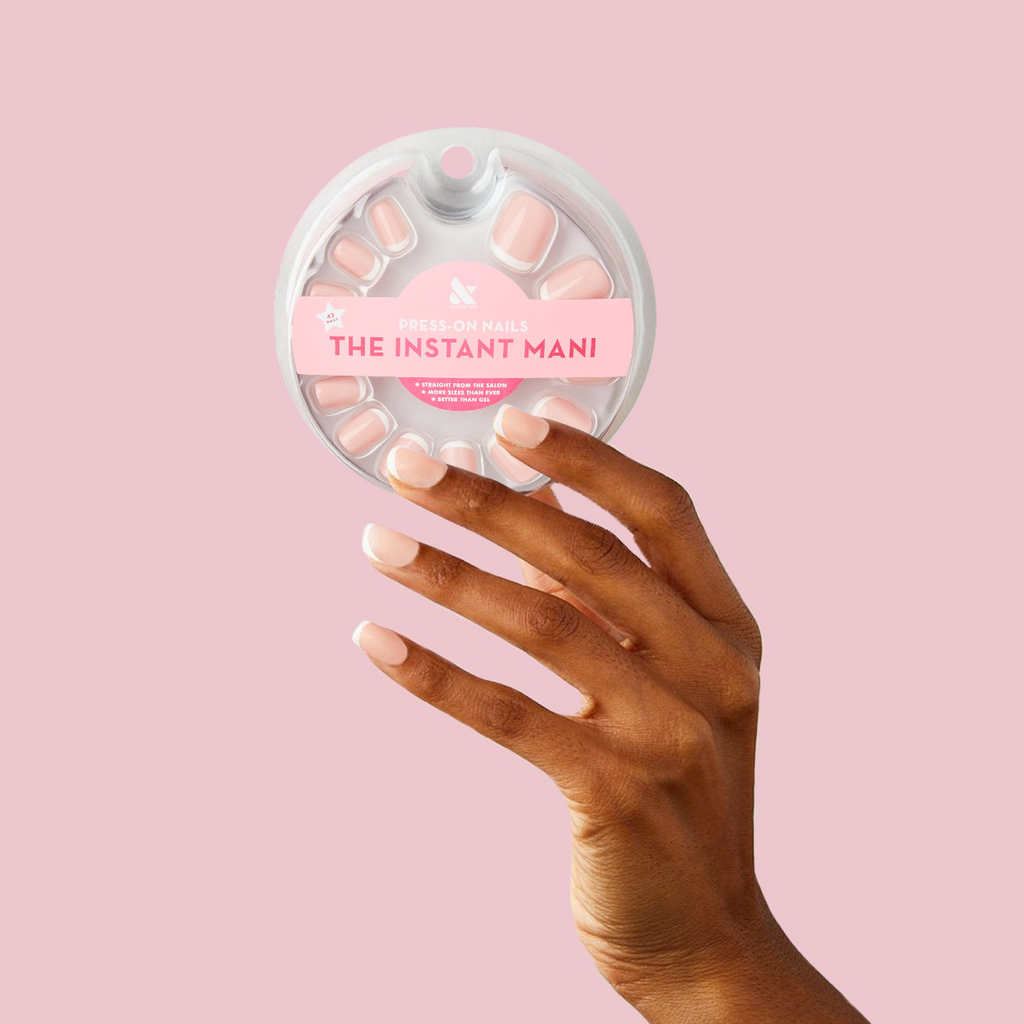 Classic French - Press-On | Extra Short | Squoval extra short nails with peachy pink base and white tips on hand holding circular packaging