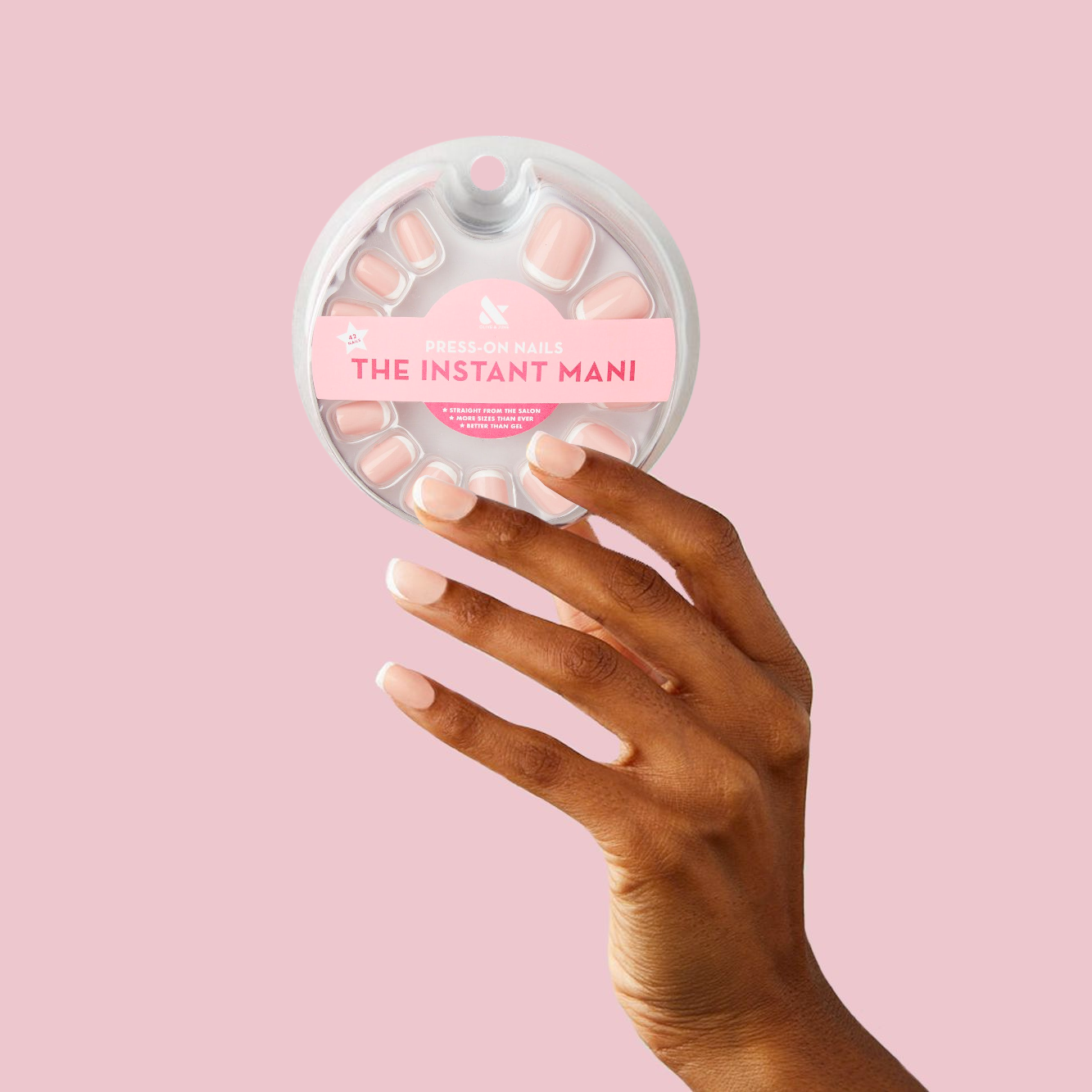 Classic French - Press-On | Extra Short | Squoval extra short nails with peachy pink base and white tips on hand holding circular packaging