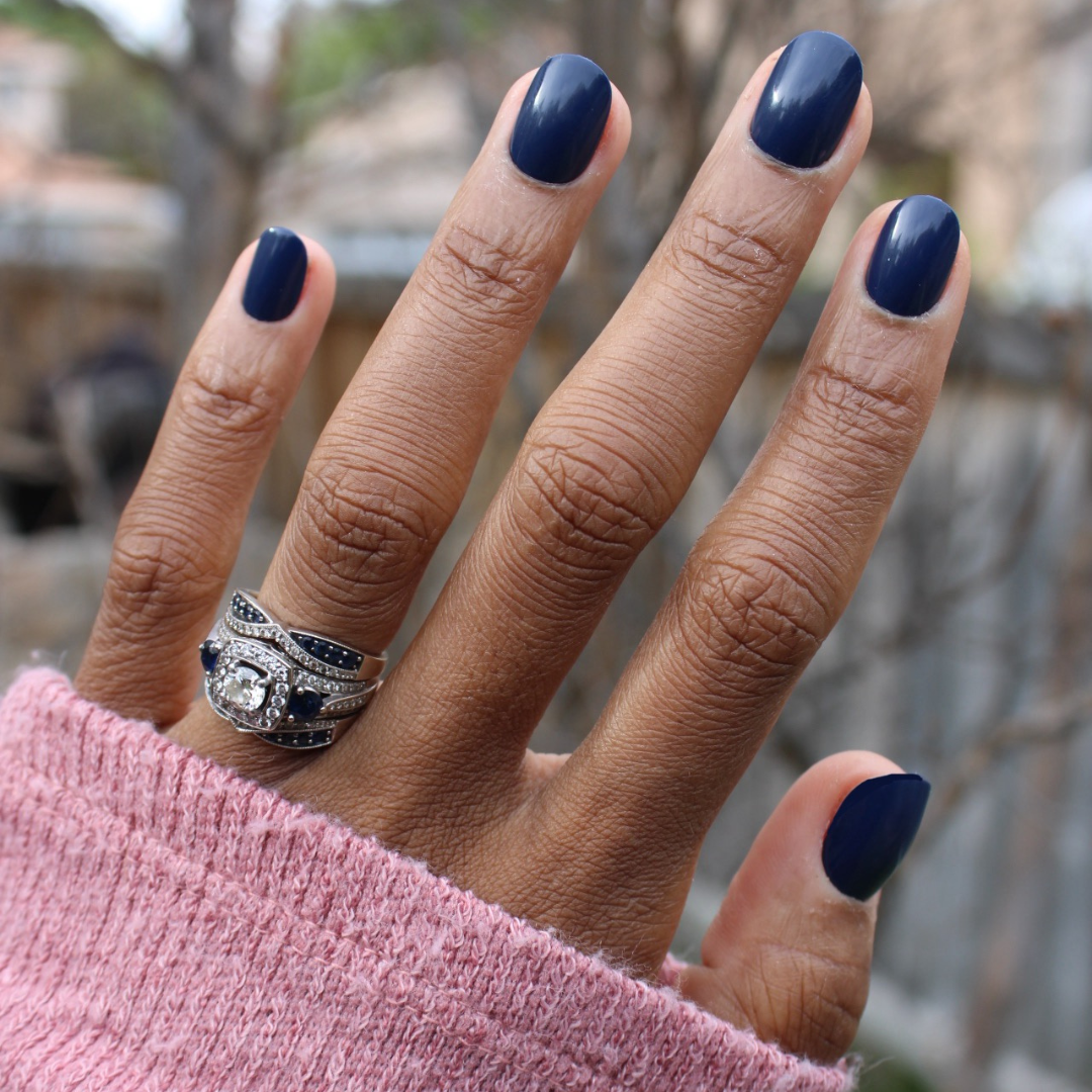 Suited | Extra Short | Round - Tab Press-On showing hand with dark navy quick dry false nails outdoors in soft pink sweater