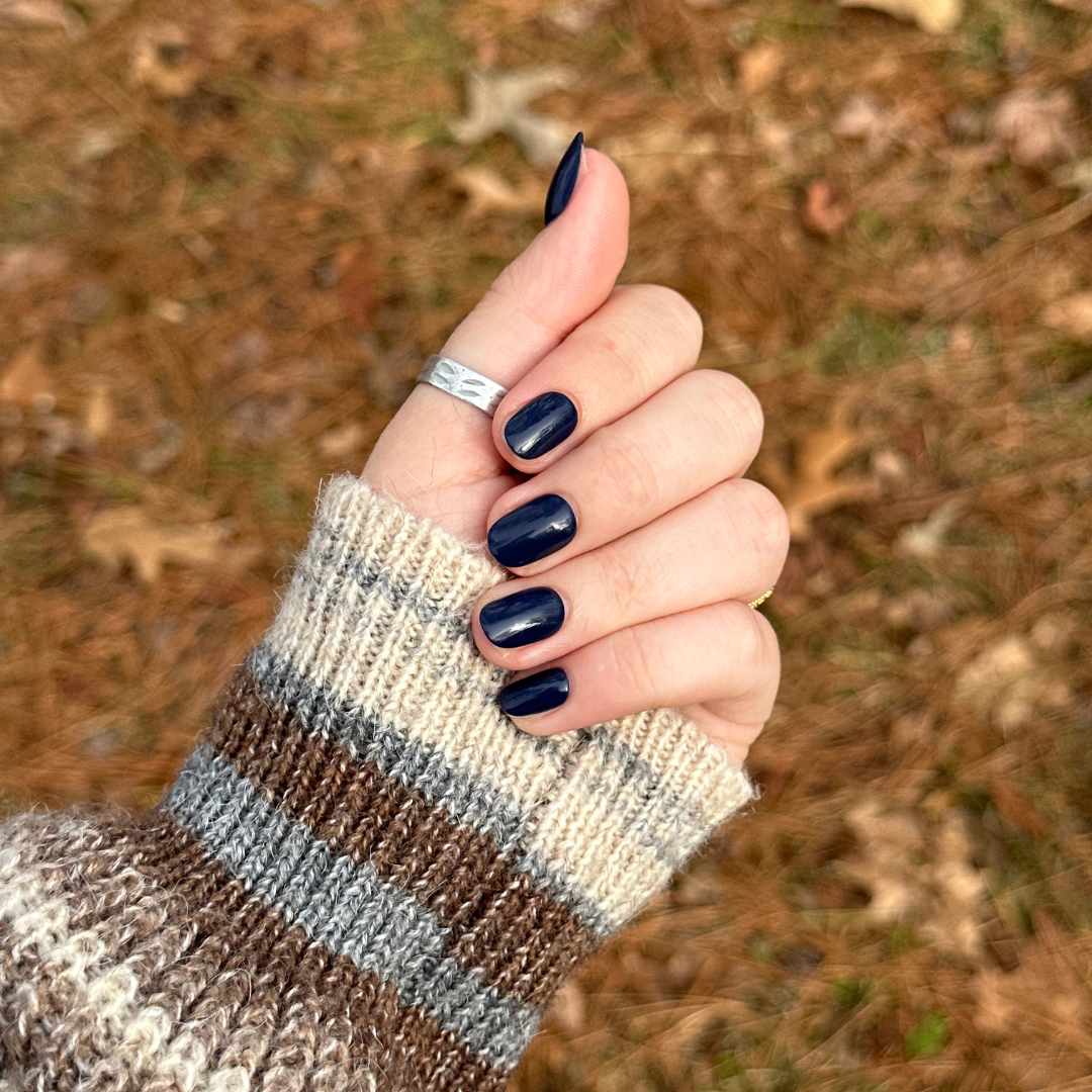 Suited | Extra Short | Round - Tab Press-On showing hand with dark navy quick dry press-on nails outdoors in knit sweater