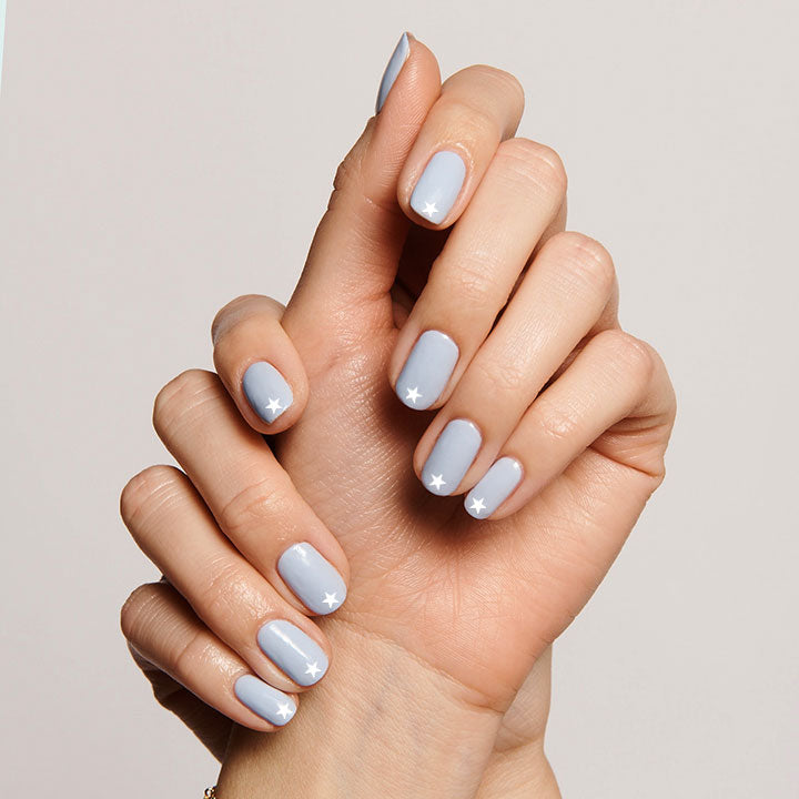 White Stars nail art stickers with small white star designs on pastel blue manicure nails by Olive and June