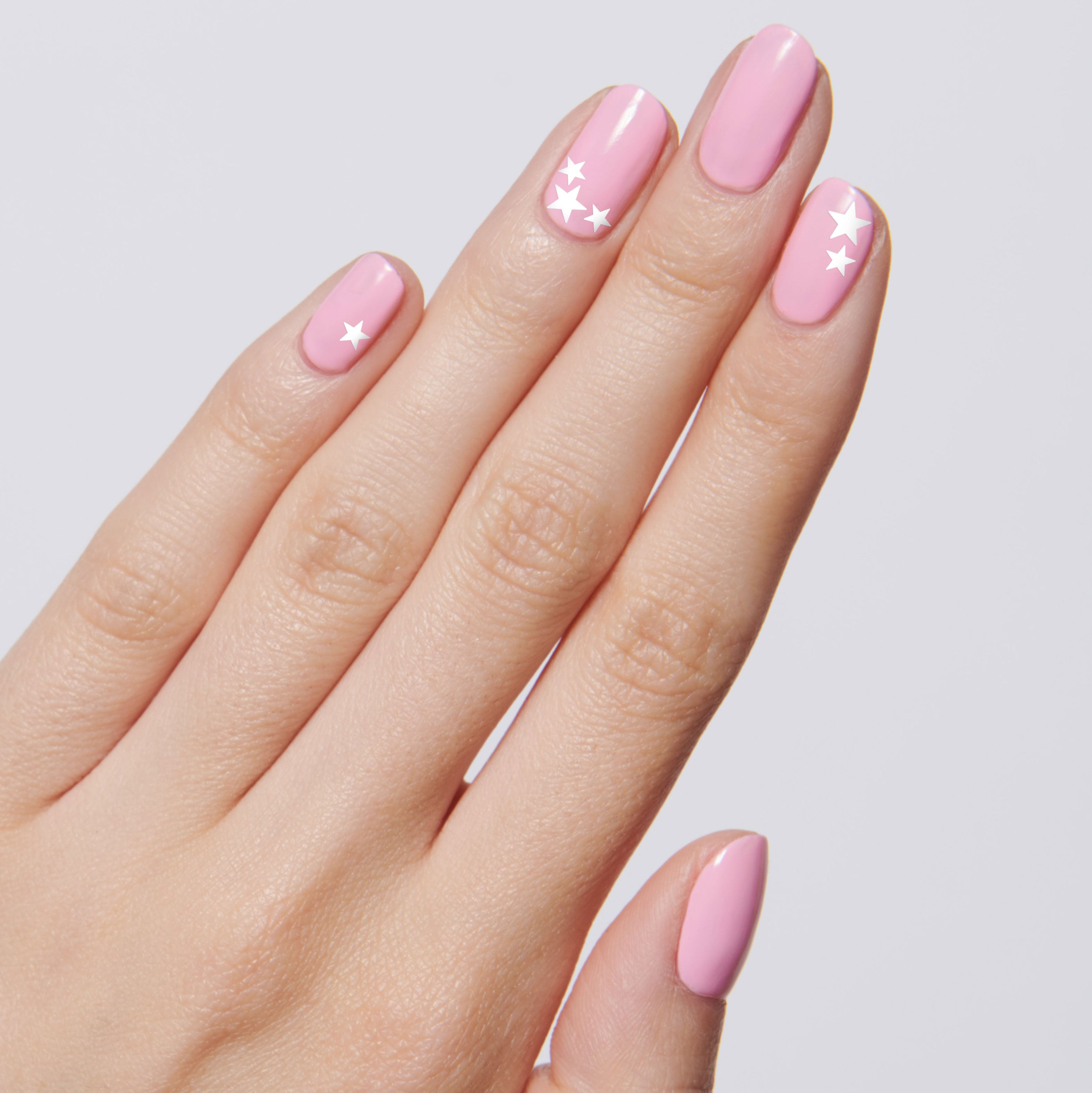 White Stars nail stickers with white star designs on soft pink polished nails for a delicate manicure look