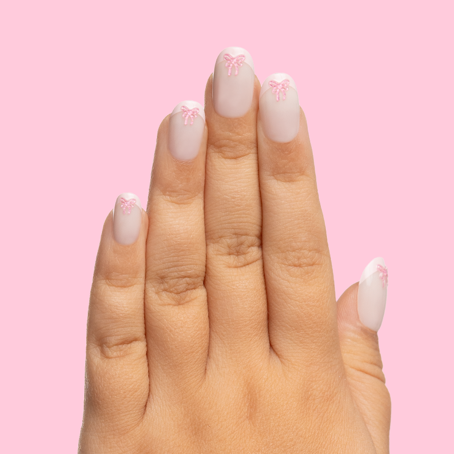 Wrapped in Pink - Pressies | Short Medium | Round showing baby pink french mani with raised bow detail on child’s hand against pink background