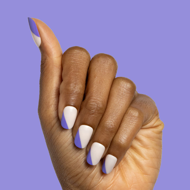 Asymmetrical French | Short | Squoval - Tab Press-On nails with indigo diagonal tips on neutral base on hand against purple background