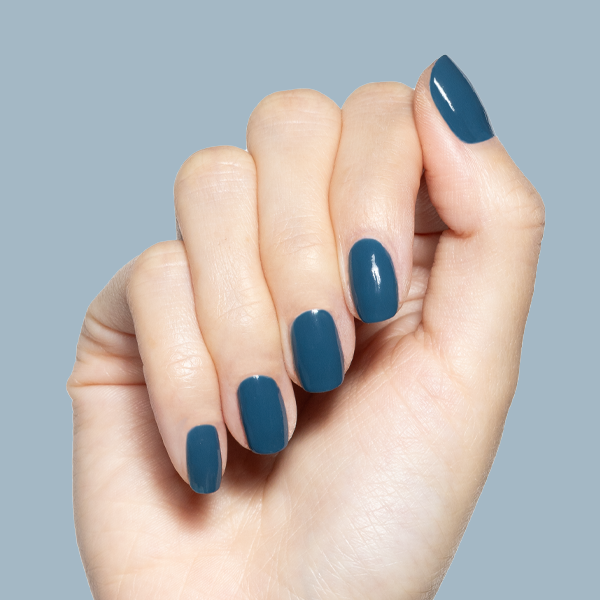 Hand with Bodysuit gel polish manicure in dusty cool teal on medium natural nails against soft blue background