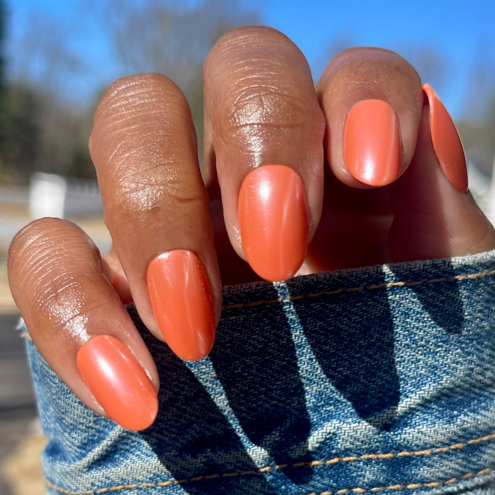 Bounce Back Chrome - Press-On | Medium | Oval bright tangerine orange chrome press-on nails on hand outdoors in natural light