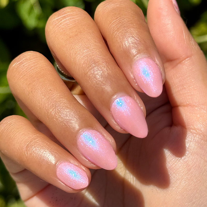 Hand with soft pink nails featuring iridescent shimmer in natural light showcasing Candy Shoppe manicure polish