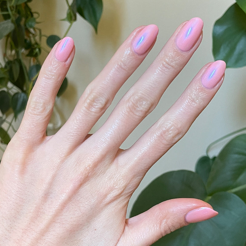 Hand with Candy Shoppe manicure showing smooth pink nails with subtle iridescent shimmer in natural light