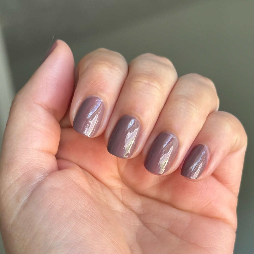 Hand showing glossy Clocking Out Early neutral minky brown gel polish manicure in natural light
