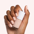 hand holding cold foam pls nail polish bottle showing shimmery neutral beige manicure with smooth, long-lasting finish