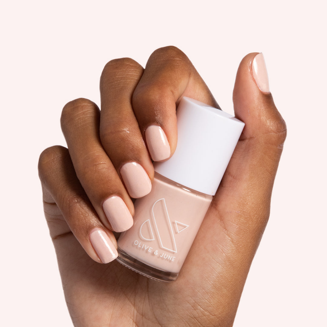 hand holding cold foam pls nail polish bottle showing shimmery neutral beige manicure with smooth, long-lasting finish