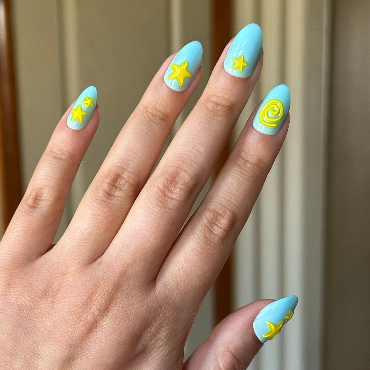 Fun Zone - Press-On | Medium | Almond nails in bright blue with raised yellow star and swirl accents for quick at-home mani