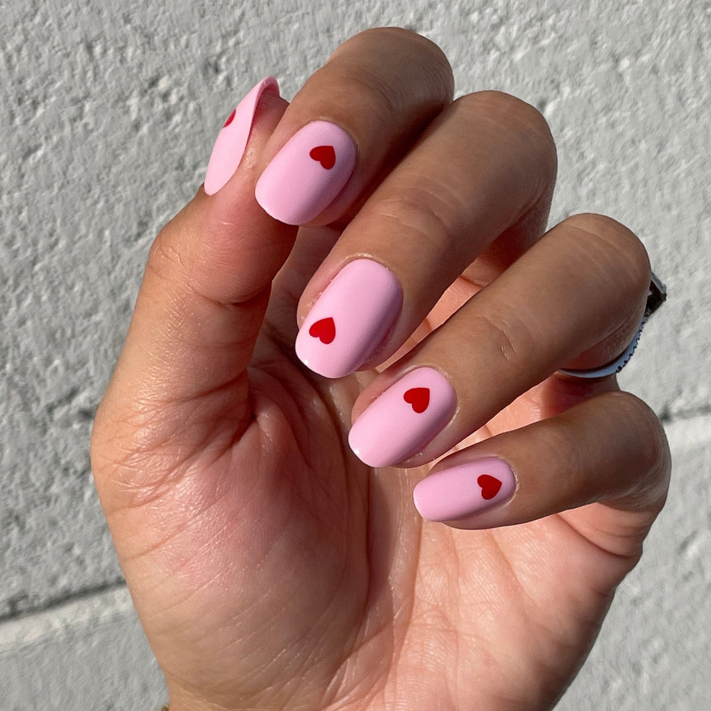 Pink Perfect Heart - Press-On | Round | Short with soft pink base and red mini heart designs on natural nails in sunlight