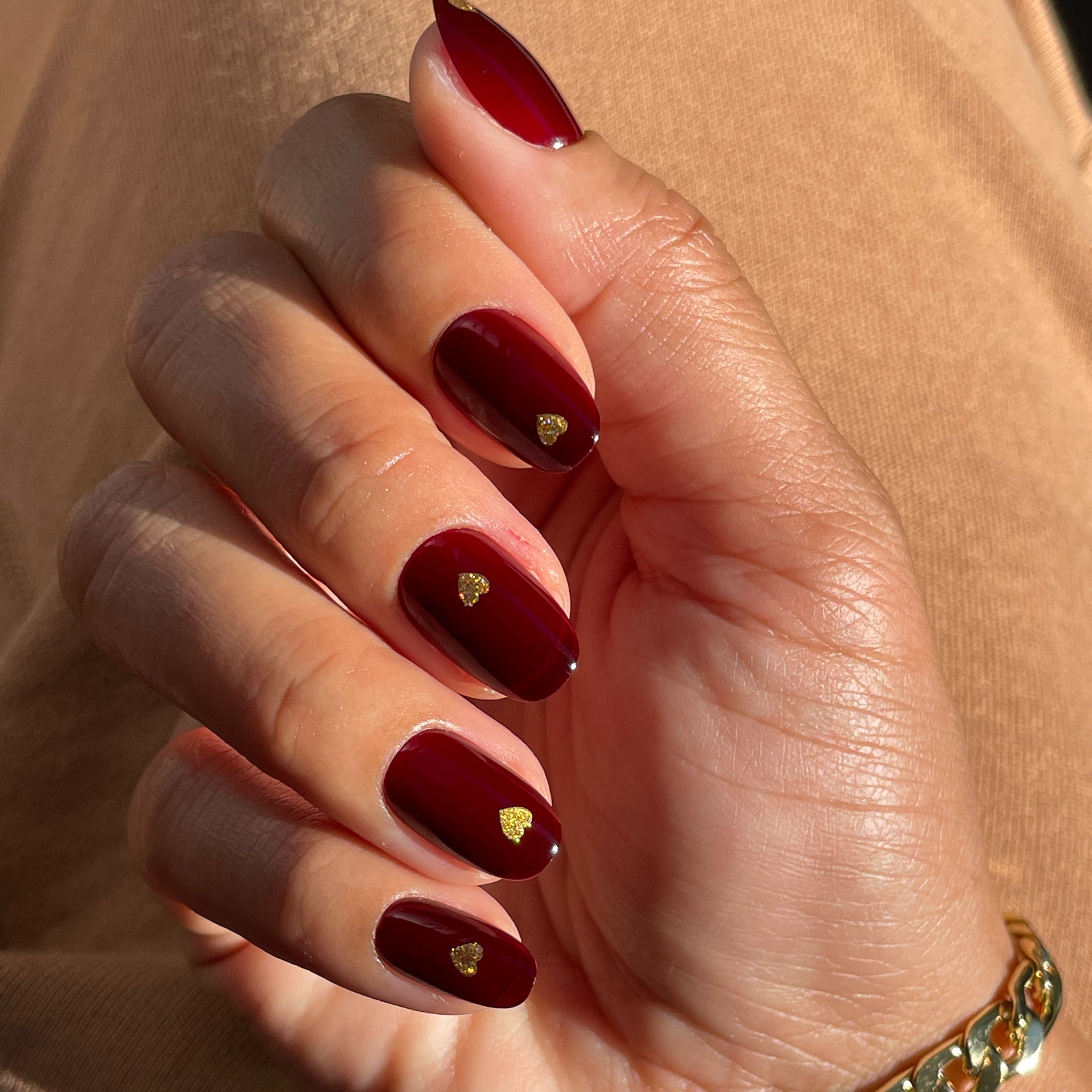 Gold Vampy Heart - Press-On | Short | Round featuring short round nails with vampy red polish and small gold heart accents manicure