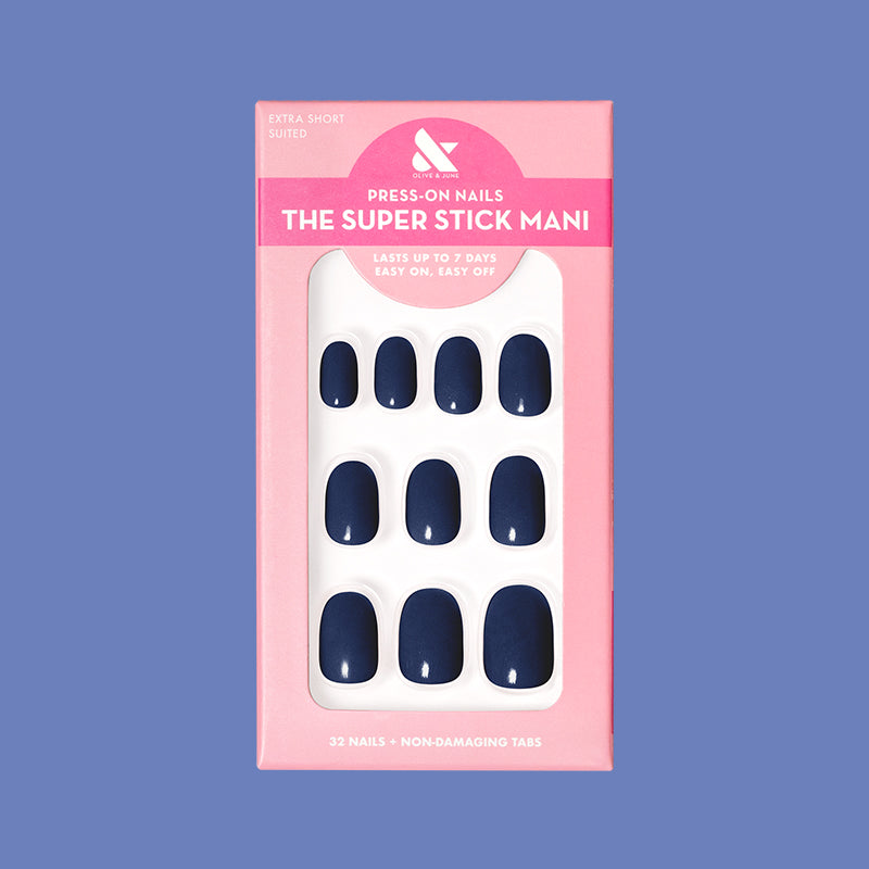 Suited | Extra Short | Round - Tab Press-On showing dark navy false nails in pink packaging on solid blue background