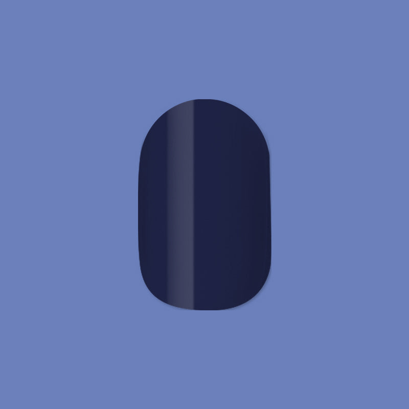 Suited | Extra Short | Round - Tab Press-On showing a single dark navy quick dry polish false nail on muted blue background