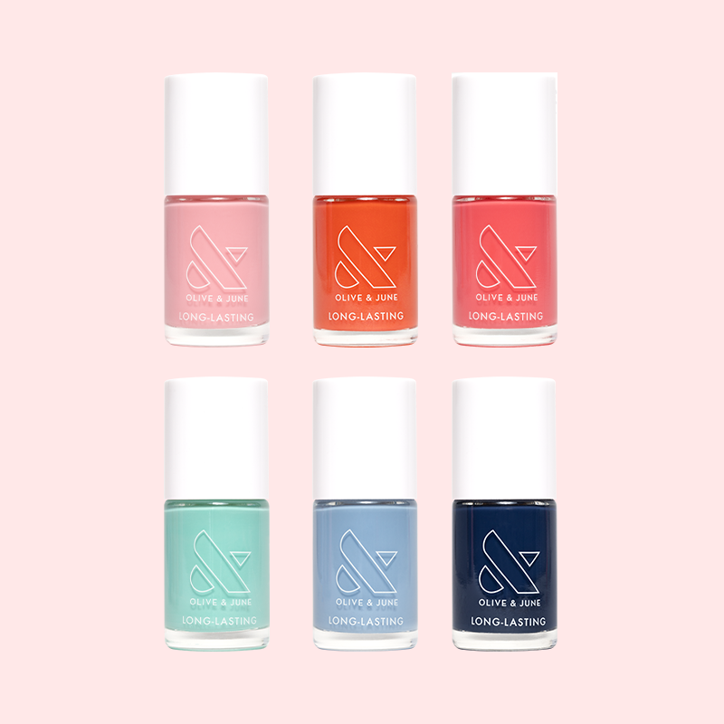 Six colorful nail polish bottles from the Summer Polish Set by Olive and June arranged on a pale pink background
